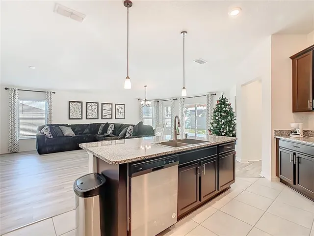 a kitchen with stainless steel appliances granite countertop a sink a stove and a wooden floors