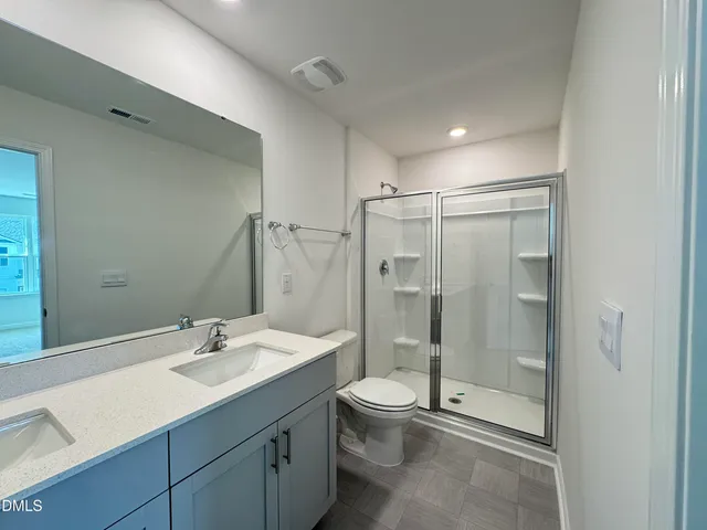 a bathroom with a shower sink mirror and toilet