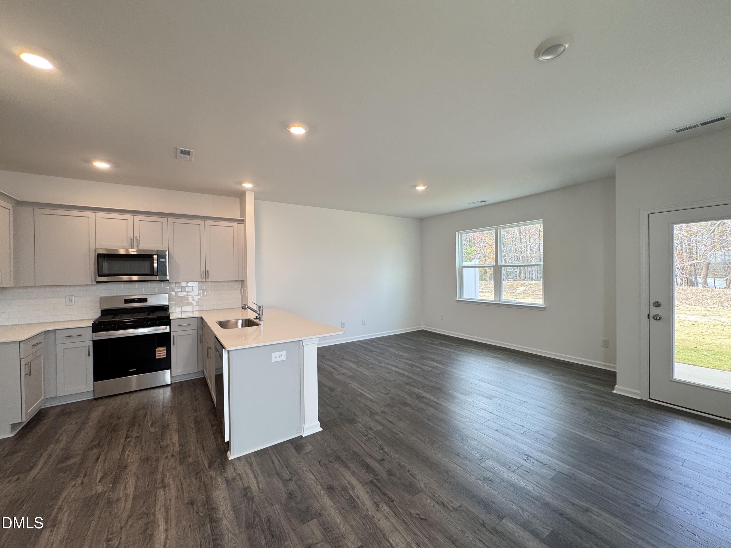 419 Belgian Red Way Wake Forest, NC 27587 - Photo 5 of 18 a kitchen with stainless steel appliances a stove top oven a sink a refrigerator with wooden floors and cabinets