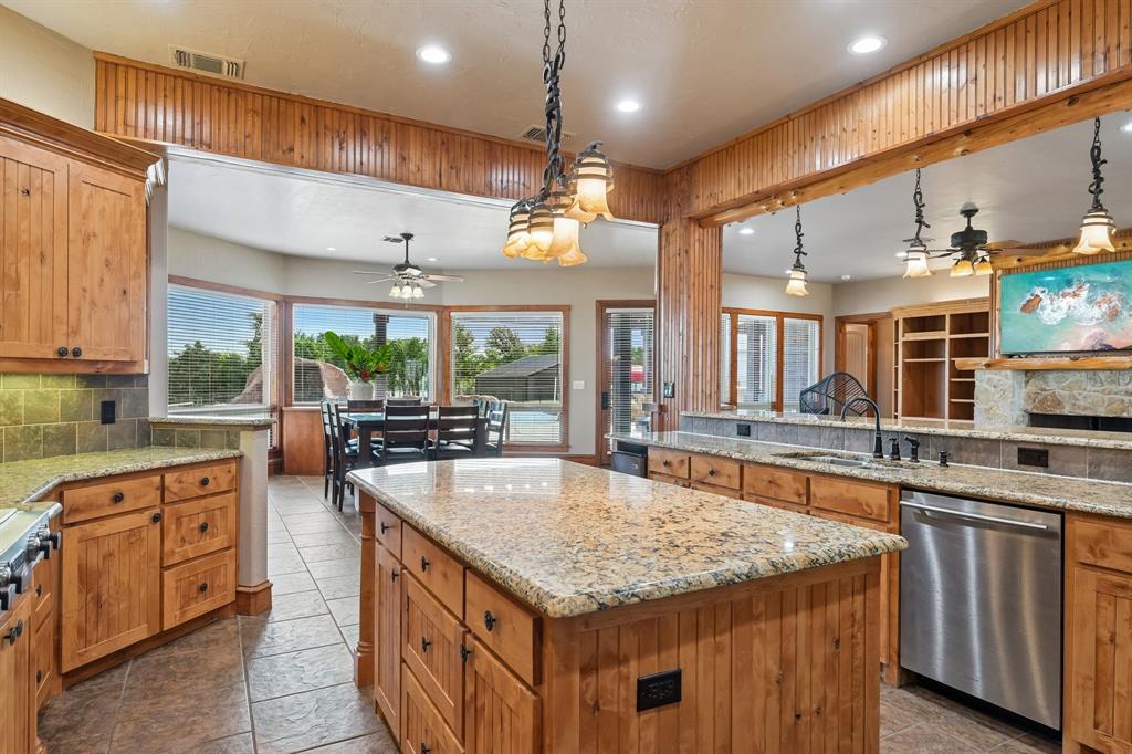 2085 Switzer Road Sanger, TX 76266 - Photo 12 of 39 Spacious kitchen featuring a central island with granite countertops, wood-finish cabinetry, tile flooring, and stainless steel appliances