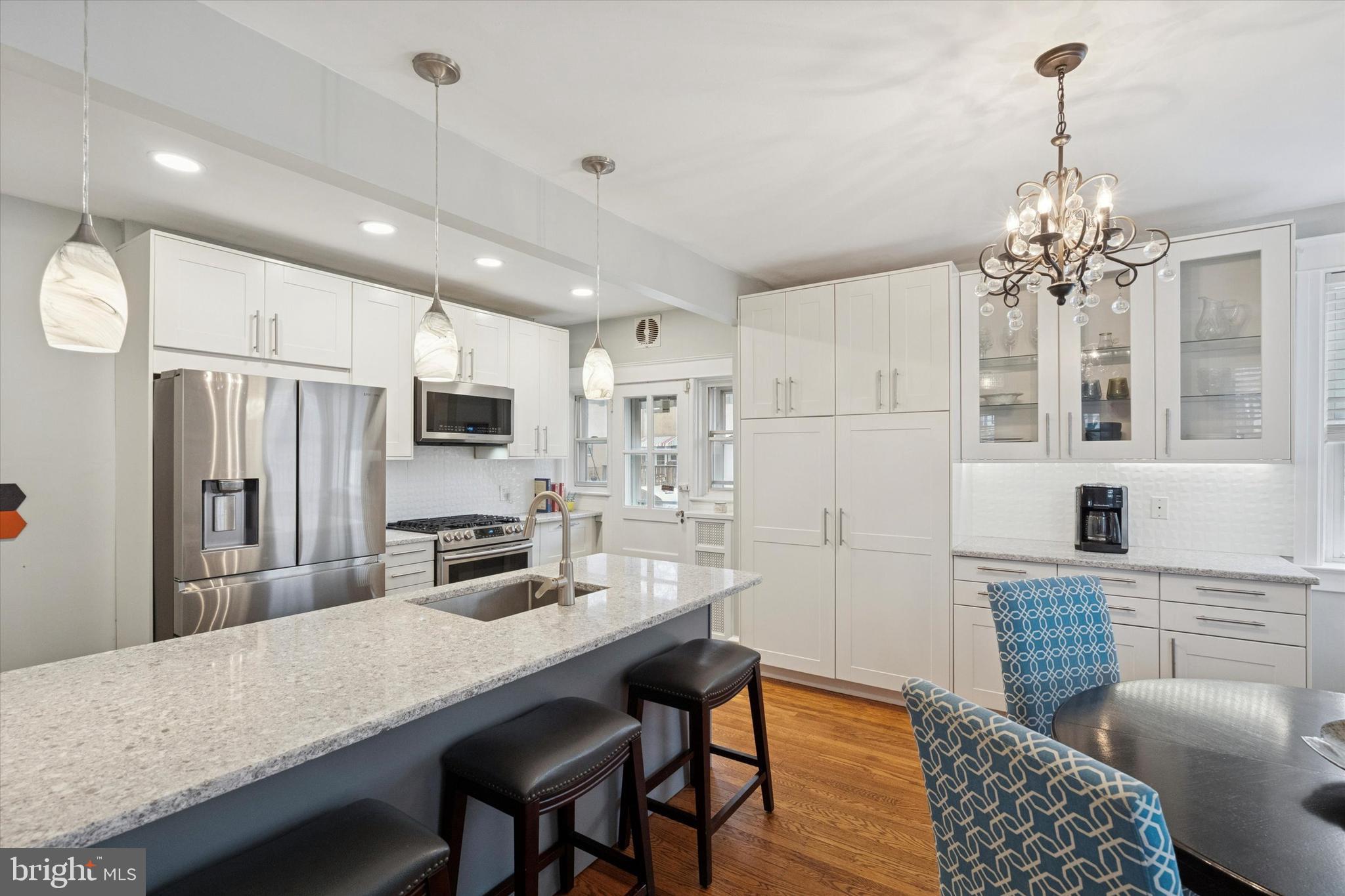 28 Chatham Road Ardmore, PA 19003 - Photo 7 of 32 a kitchen with stainless steel appliances granite countertop a refrigerator oven a sink dishwasher a dining table and chairs with wooden floor