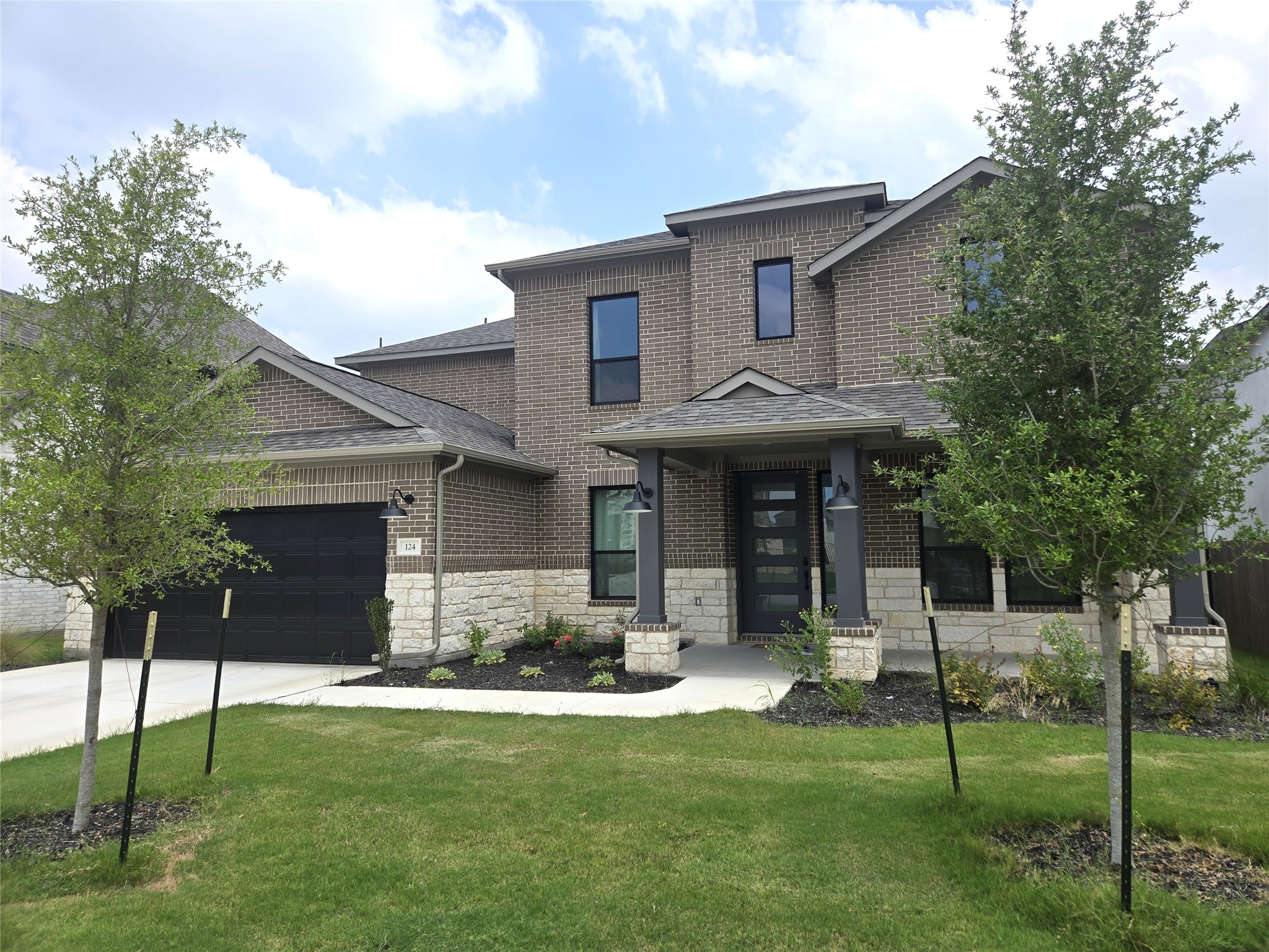 124 Ribera Drive Liberty Hill, TX 78642 - Photo 2 of 40 A striking modern facade with contrasting brick and stone offers a welcoming entryway and practical attached garage.