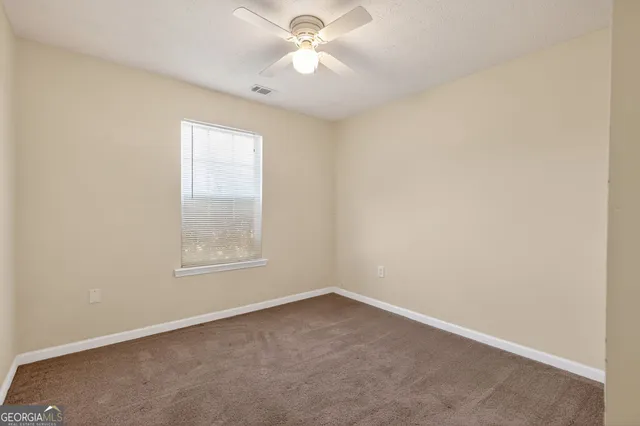 an empty room with a window and a fan