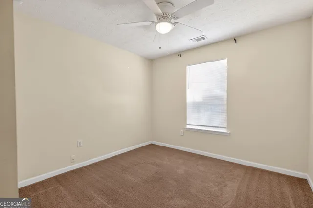 an empty room with a window and ceiling fan