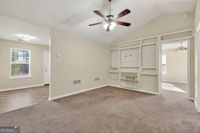 an empty room with windows and fan