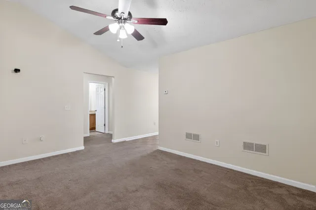 a view of an empty room and chandelier fan