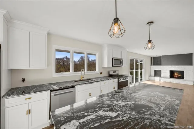 a kitchen with granite countertop a stove a sink and a refrigerator