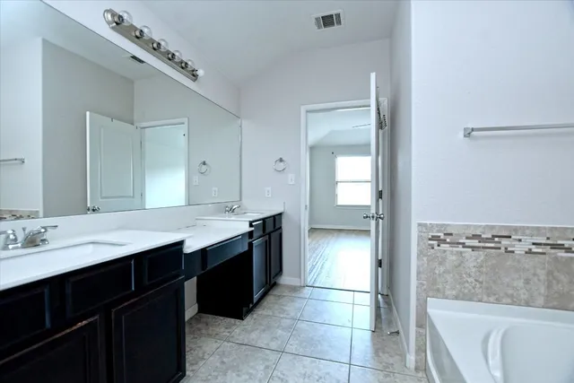 a spacious bathroom with a granite countertop sink a bathtub and a mirror