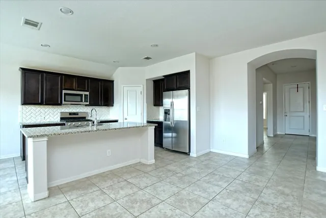 a kitchen with stainless steel appliances granite countertop a refrigerator and a stove top oven