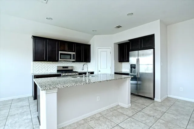 a kitchen with stainless steel appliances granite countertop a refrigerator a stove a sink a microwave and cabinets