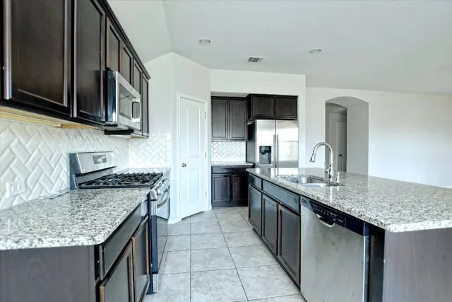 a kitchen with stainless steel appliances granite countertop a sink stove and refrigerator