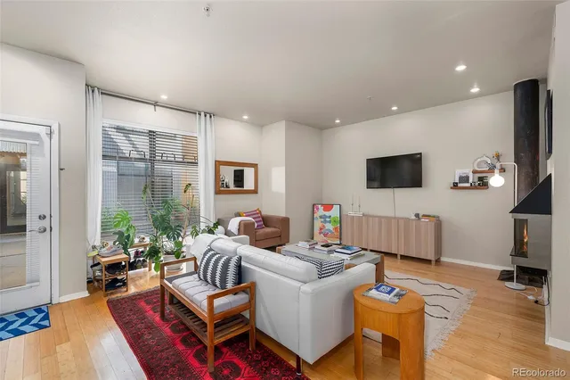 a living room with furniture a flat screen tv and a refrigerator