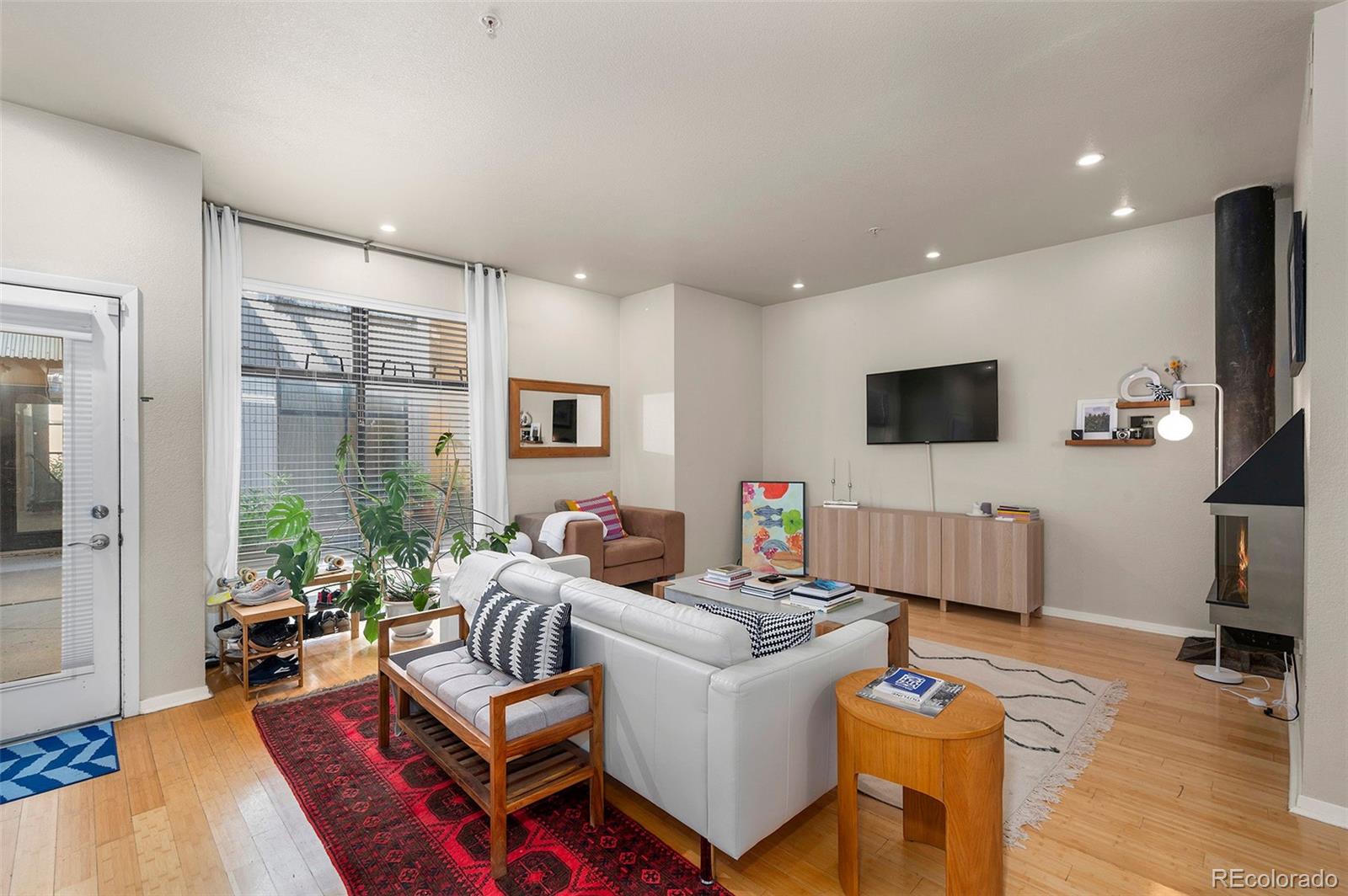 3225 Blake Street, Unit 4 Denver, CO 80205 - Photo 4 of 23 a living room with furniture a flat screen tv and a refrigerator