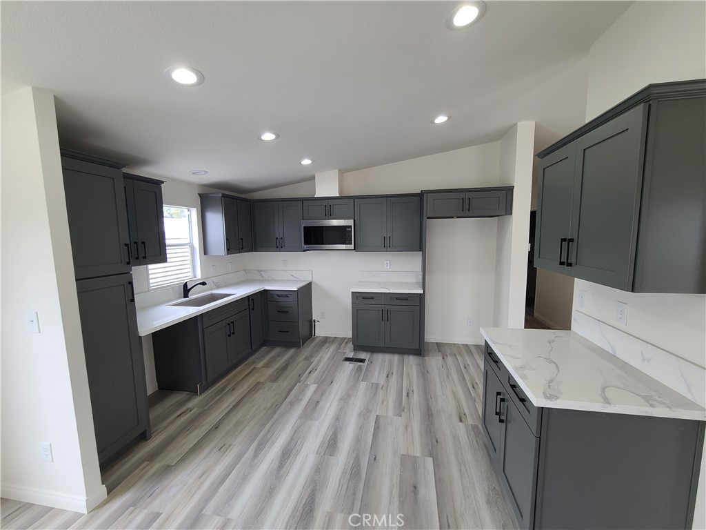 840 East Foothill Boulevard, Unit 64 Azusa, CA 91702 - Photo 14 of 25 a large kitchen with a large counter top a sink stainless steel appliances and cabinets