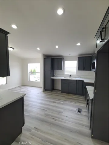 a large kitchen with a large counter top a sink stainless steel appliances and cabinets