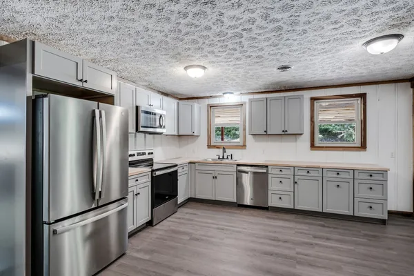 a kitchen with granite countertop stainless steel appliances a refrigerator cabinets and wooden floor