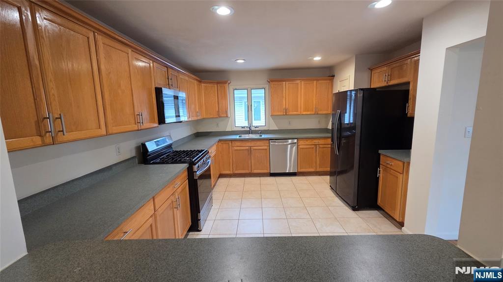 755 Edgewater Avenue, Unit 2 Ridgefield, NJ 07657 - Photo 6 of 13 a kitchen with stainless steel appliances granite countertop a refrigerator a stove a sink and a microwave