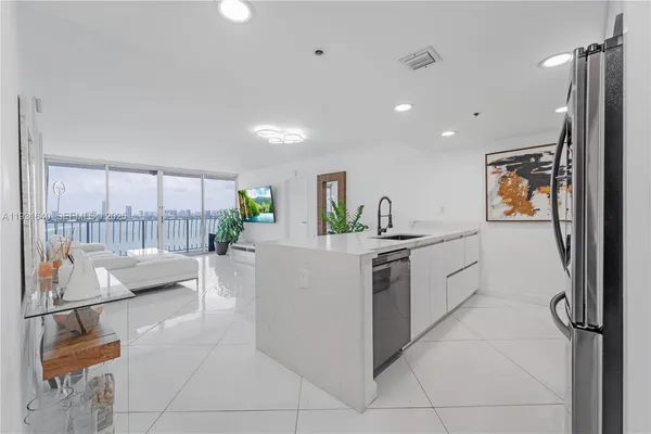 a kitchen with stainless steel appliances kitchen island granite countertop a refrigerator and a sink