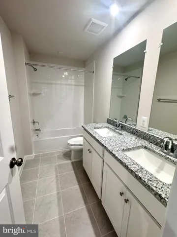 a bathroom with a granite countertop sink a toilet and a mirror