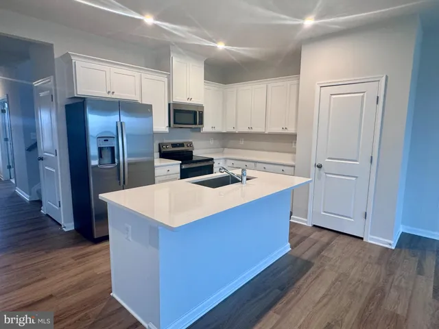 a kitchen with stainless steel appliances granite countertop a stove a refrigerator a sink a microwave oven with wooden floor and cabinets