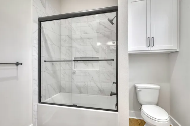 a bathroom with a shower a toilet and a window