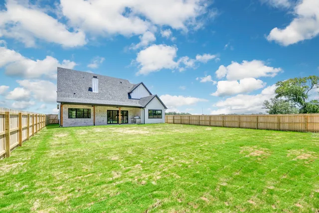 a view of a big house with a big yard and large trees