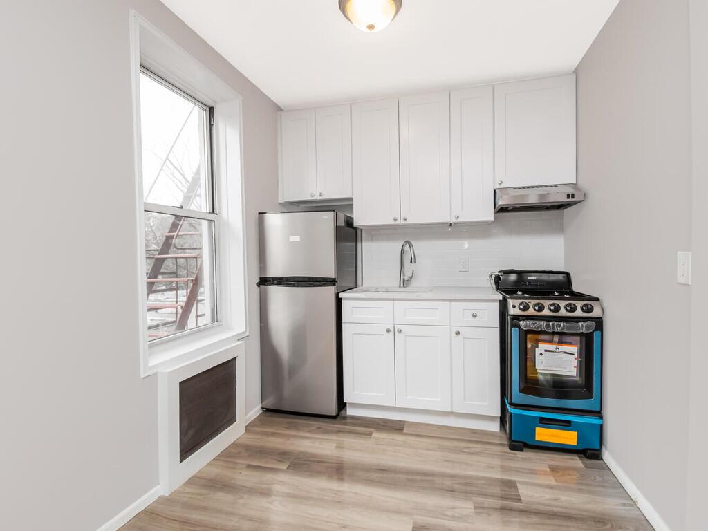 6535 Broadway, Unit 4B Bronx, NY 10471 - Photo 6 of 11 Kitchen featuring light countertops, stove, freestanding refrigerator, white cabinets, and a sink