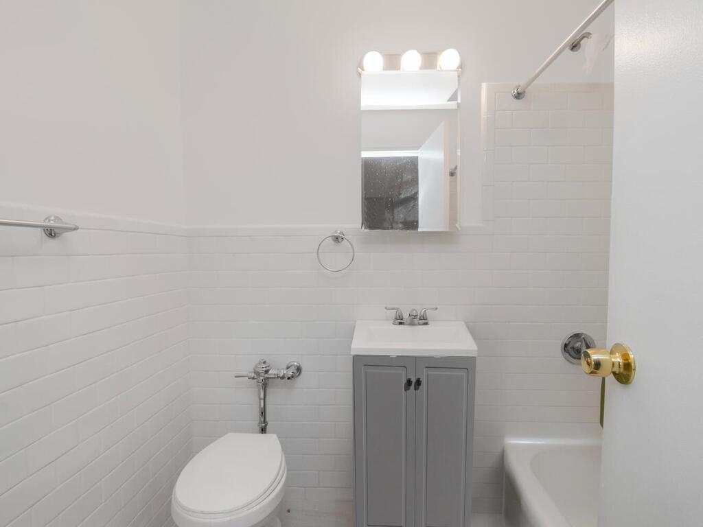 6535 Broadway, Unit 4B Bronx, NY 10471 - Photo 7 of 11 Bathroom with shower / bathtub combination, toilet, a wainscoted wall, vanity, and tile walls
