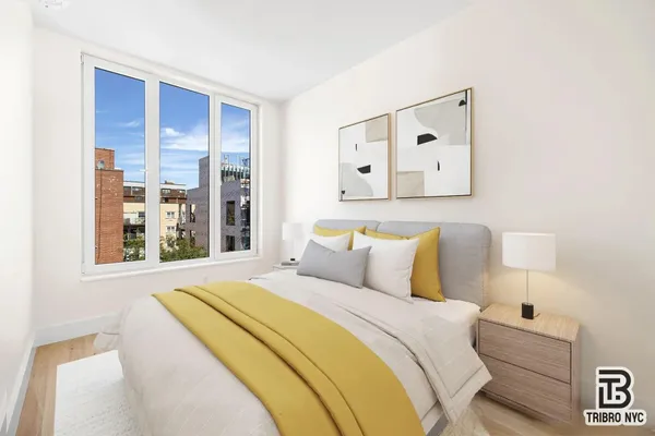 a bedroom with a bed and a large mirror next to a window
