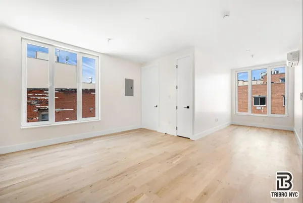 a view of an empty room with a window and wooden floor