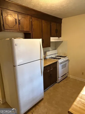 a white refrigerator freezer and a stove sitting inside of a kitchen