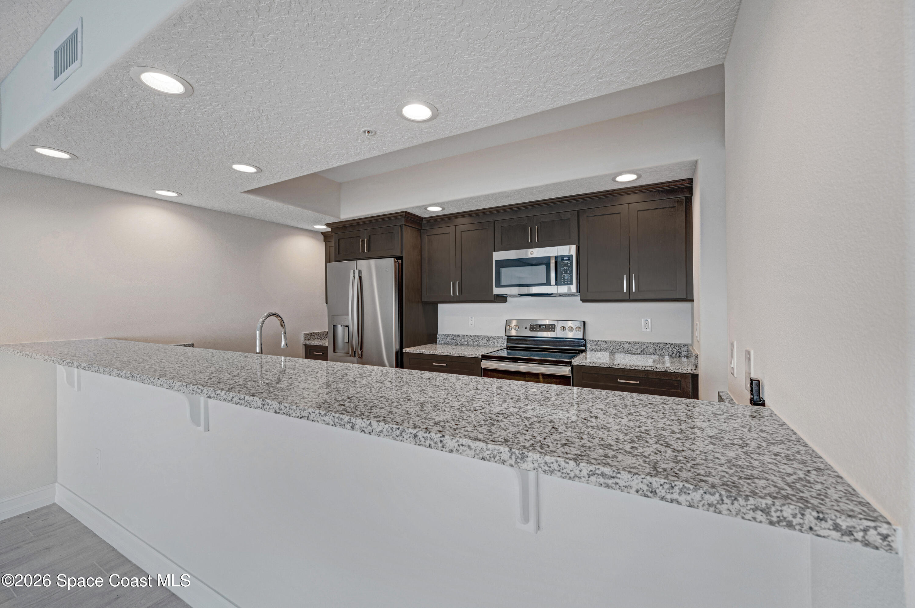 1805 Riverside Drive, Unit 304 Titusville, FL 32780 - Photo 26 of 46 a kitchen with stainless steel appliances granite countertop a sink a stove and a microwave
