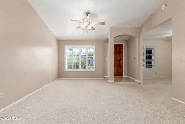 an empty room with chandelier fan and windows