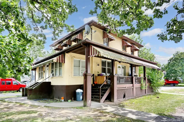 a view of a white house with large windows and a small yard