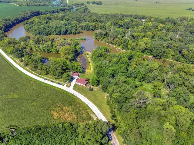 an aerial view of a residential houses with outdoor space and trees all around