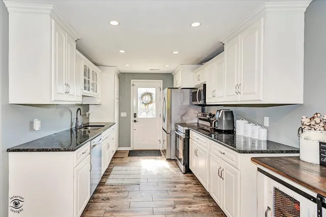 a kitchen with granite countertop a sink and dishwasher a stove top oven with white cabinets