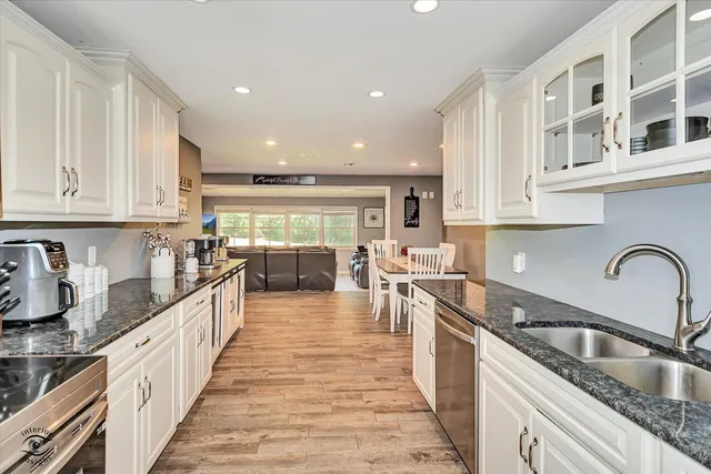 a large kitchen with stainless steel appliances granite countertop a sink and cabinets
