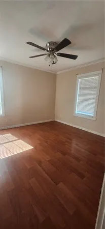 an empty room with wooden floor ceiling fan and windows