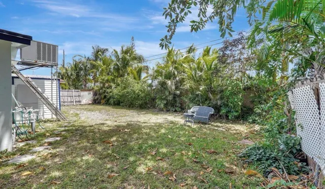 a view of a yard with table and chairs and potted plants