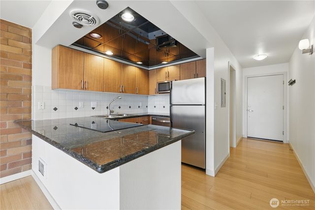 a kitchen with stainless steel appliances granite countertop a sink a refrigerator and a cabinets