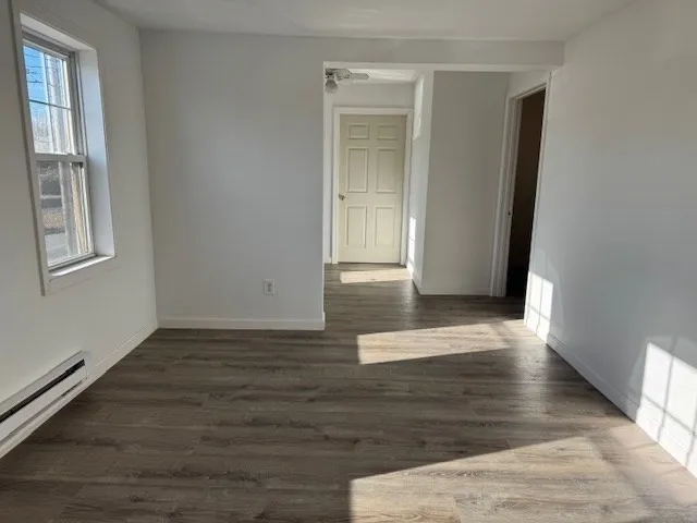 a view of an empty room with wooden floor and a window