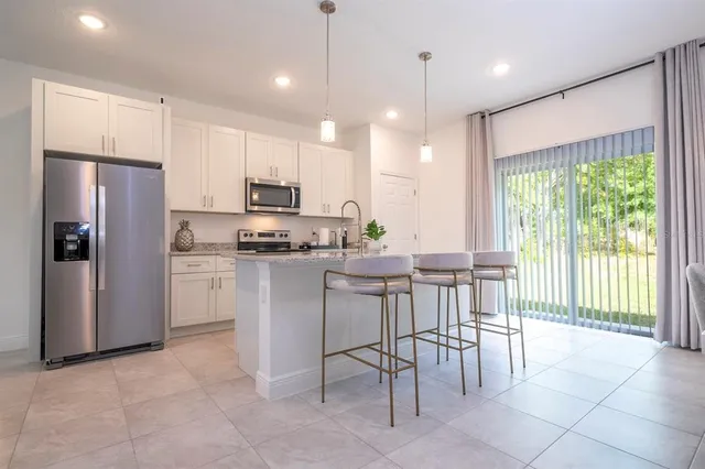 a kitchen with kitchen island white cabinets and refrigerator