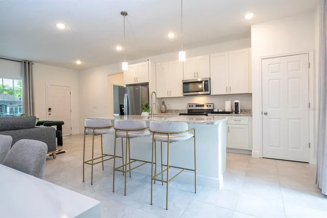 a kitchen with kitchen island granite countertop a stove a sink a refrigerator a dining table and chairs