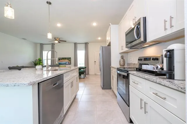 a large kitchen with stainless steel appliances kitchen island granite countertop a sink and cabinets
