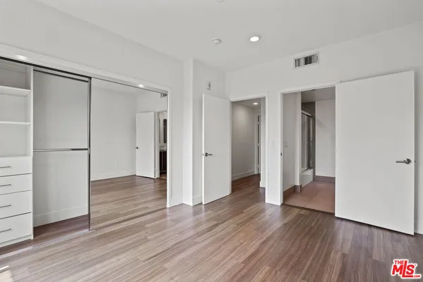 an empty room with wooden floor closet and windows