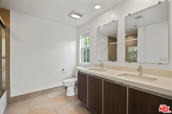 a bathroom with a double vanity sink toilet and a mirror