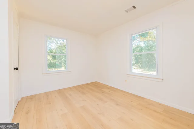 a view of a bedroom with wooden floor and window