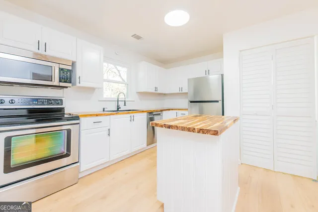 a kitchen with stainless steel appliances granite countertop a stove a sink and a microwave