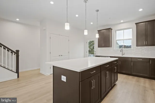 a large white kitchen with kitchen island a sink stainless steel appliances and cabinets
