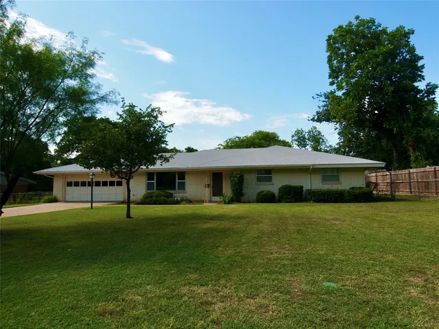 a view of an house with backyard and trees